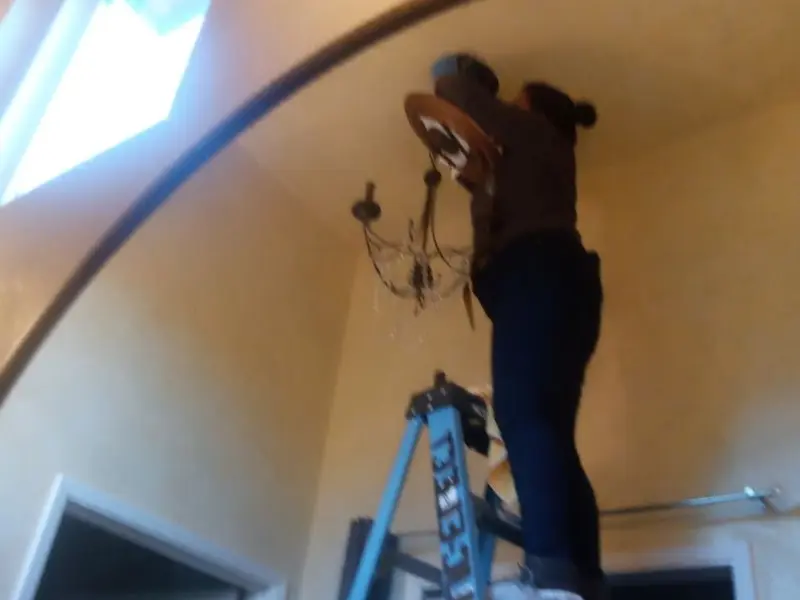 Electrician installing a chandelier in a Shady Shores residence